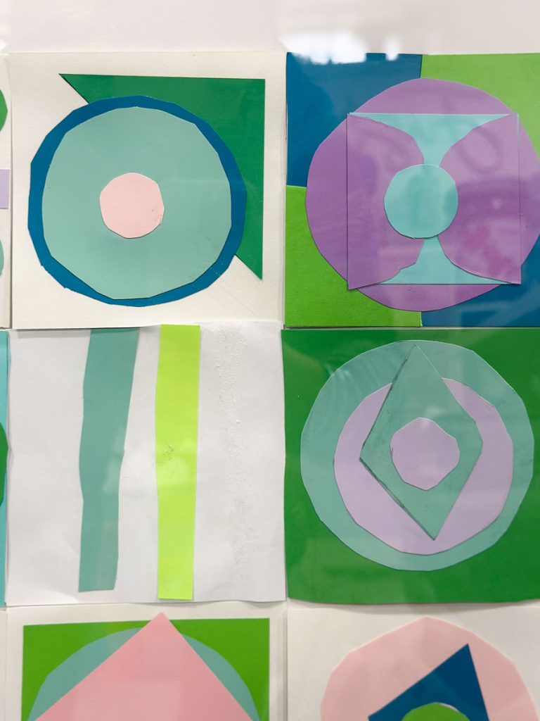 A display of colorful geometric paper art featuring circles and diamonds in shades of blue, pink, purple, and green, mounted in a grid on a white background.